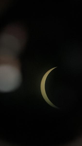 This photo captures a striking crescent shape, likely a partial solar eclipse, against a dark sky